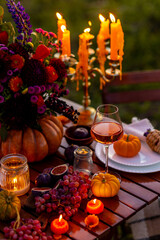 Elegant autumn decoration. Private wedding party for two, table set with floral decor, pumpkins, wine in field or meadow. Fall vibes, sunset, golden hour. Romantic surprise, marriage proposal