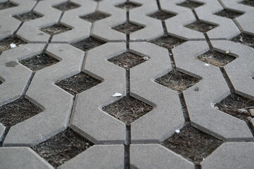 Background texture of square tiles made of gray natural stone. Concrete street covering of road, geometric paving pattern, green lawn and eco parking, green parking, sustainable development city	
