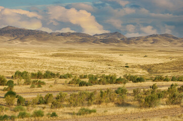 Steppe, prairie, plain, pampa. Beautiful sunset sky. Escape to the serenity of the desert, where the mountains are high, surrounded by the tranquility of the wild Desert Escape © Aleks