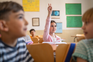 school girl raise hand to answer the teacher question