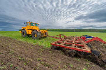 Obraz premium Spring photography, landscape with agricultural machinery, a tractor plows the land, plows a field, birds fly over arable land