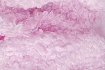 Fototapeta premium Faux fur in pale pink color. Imitation of karakul lamb skin. known as fleecy fabric, which resembles animal fur in appearance and warmth.
