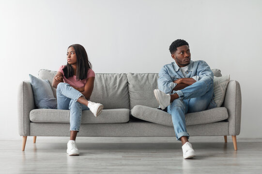 Family Conflict Concept. Stubborn black couple sit on couch back to back avoid talking after fight, offended man and woman separated on sofa ignoring one another, husband and wife not looking in eyes