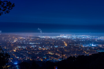 Night view of a city with lights, seen from a high vantage point.