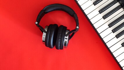 Headphones and keys of electric piano on red background, top view. Concept of creativity. Place for text.