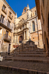 Stone steps lead to a historic building in a European town under a blue sky.