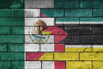 Fototapeta premium colourful painted big national flag of mexico and flag of mozambique on a massive old brick wall background. concept