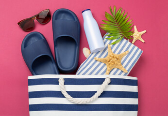 Blue beach bag with summer accessories on color background, top view
