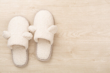 Soft teddy slippers on wooden background, top view
