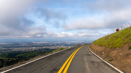 Scenic road overlooking a city under a cloudy sky in California