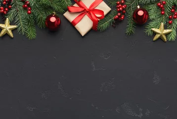 Fotobehang Traditional Christmas ornament. Green fir with red balls, golden stars and gift box on black background, top view, copy space © Prostock-studio