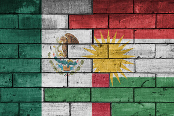 colourful painted big national flag of mexico and flag of kurdistan on a massive old brick wall background. concept