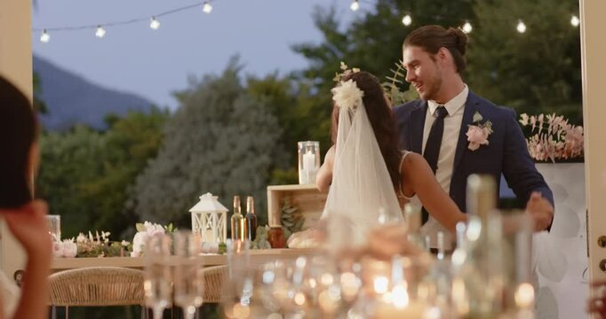 Diverse couple sharing first dance on patio raising arm twirling bride dipping under string lights