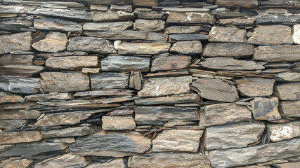 Old stone wall background. Stones in facade decoration. Layers and cracks in stone.