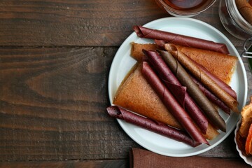 Tasty fruit leather rolls on wooden table, flat lay. Space for text