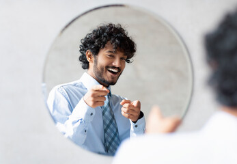 You're handsome. Confident indian businessman pointing at mirror in bathroom with two fingers, man...