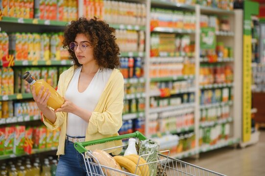 Customer choosing juice bottle in supermarket groceries section