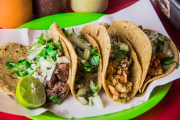 An enticing arrangement of tacos filled with fresh meats, topped with onions and cilantro, served with lime on a vibrant green plate, perfect for taco lovers.