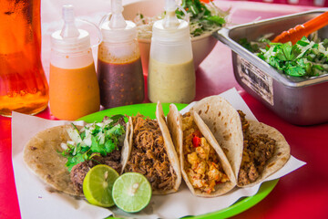 A colorful selection of tacos displayed with various flavorful condiments like salsa and creamy sauces, enhancing the culinary experience on a lively table setting.