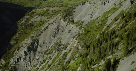 Aerial shot soaring in on beautiful rocky mountain side with scattered trees