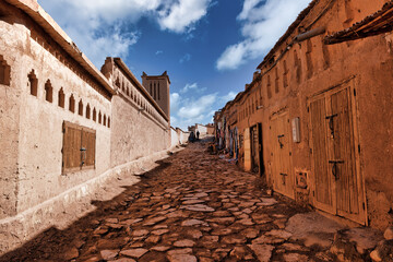 Sun-drenched alleyway, adobe buildings.