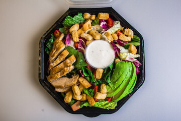 This appealing image captures a delicious chicken salad with vibrant greens, creamy dressing, avocado, and croutons, ideal for health-conscious diners or meal prep.