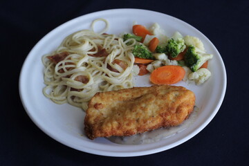A crispy fried chicken fillet served over a bed of pasta and accompanied by a medley of colorful steamed vegetables, presenting a delightful and nutritious dining option for all.