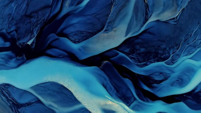 Aerial footage of braided glacial river system in abstract patterns with turquoise and blue water flowing through the landscape forming textures.