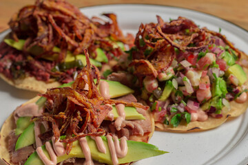 A vibrant display of tostadas topped with avocado, beans, fried onions, and sauces, served on a plate, showcasing the rich flavors of traditional Mexican cuisine beautifully.