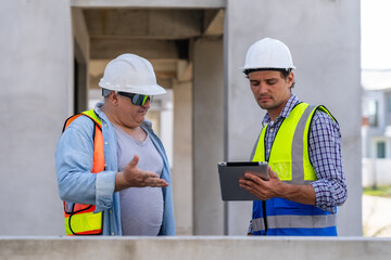Two engineers holding tablets checking and planning work in construction project. Teamwork concept.