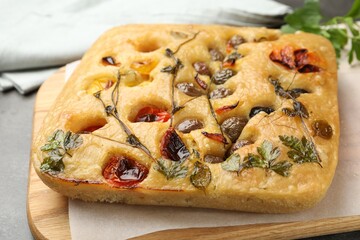 Delicious focaccia with flowers made of vegetables on light grey table, closeup