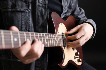 Obraz premium Man playing guitar on black background, closeup