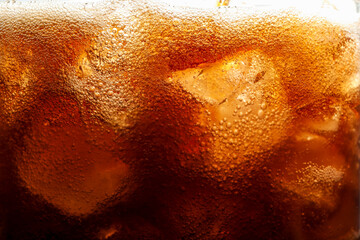 Refreshing cola with ice as background, macro view