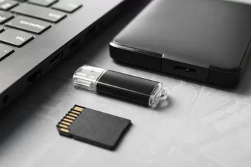 Zelfklevend Fotobehang Flash drive, SD memory card, external hard disk and laptop on gray textured table, closeup © New Africa
