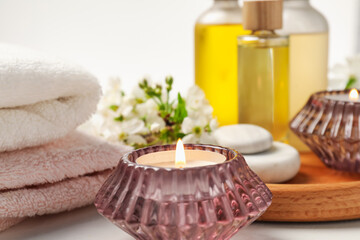 Burning candles and spa products on white table, selective focus