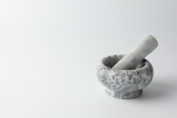 Marble mortar with pestle on white background, space for text