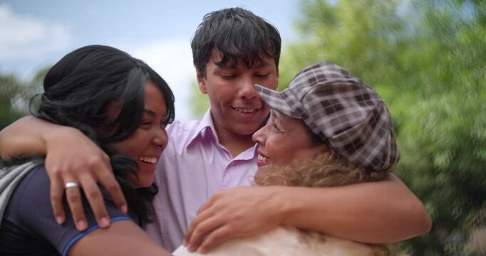 Young friends meeting outdoors and hugging each other on a sunny day.