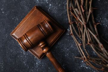 Crown of thorns and judge's gavel on dark textured background, top view