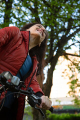 Beauty smiling woman long brown hair biking on bicycle on spring trees background and looking....