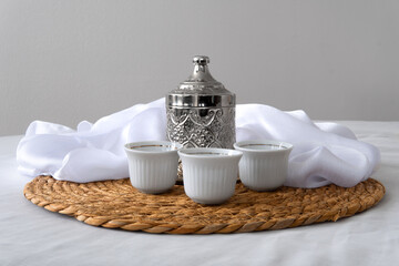 Elegant Coffee Set with Engraved Metal Pot, Porcelain Cups, Sugar Bowl, and Woven Mat on Clean Tabletop