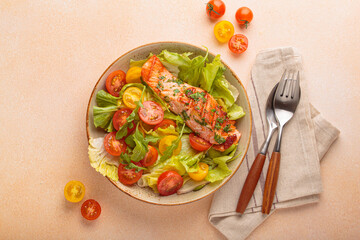 Grilled salmon fillet with fresh green lettuce, colorful cherry tomatoes salad top view, beige pastel background, healthy eating habits