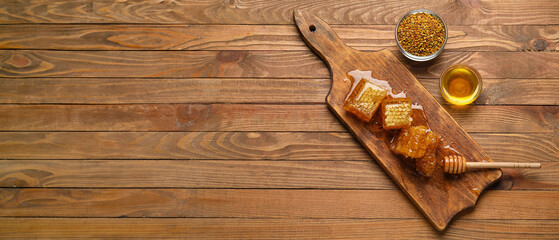 Bowl of honey, combs and bee pollen on wooden background