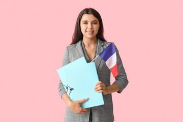 Fototapeta premium Female French language teacher with folders and flag on pink background
