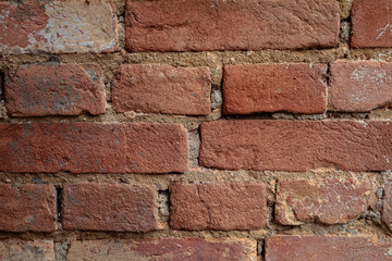 Detalhe de parade de tijolos antigos com textura rústica de tom avermelhado.