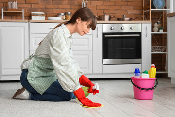 Pretty young woman with rag and sprayer cleaning floor at home