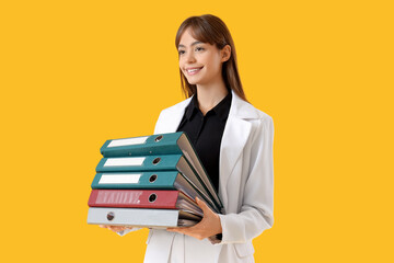Beautiful businesswoman with folders on yellow background