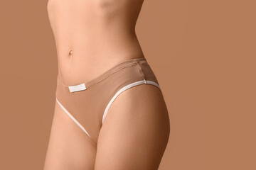 Beautiful young woman in beige underwear on brown background, closeup