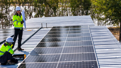 Two workers in safety gear installing solar panels on a rooftop, highlighting renewable energy,...