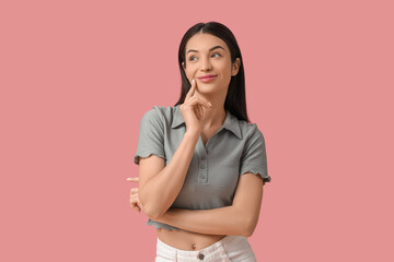 Obraz premium Beautiful young thoughtful smiling woman on pink background