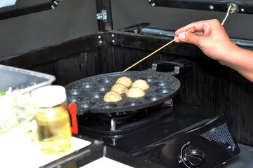 the process of cooking takoyaki on a baking pan